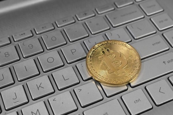 A physical Bitcoin coin resting on a laptop keyboard