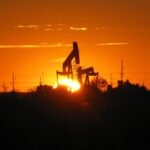 A pump jack silhouetted against the setting sun at an oil well in Texas.