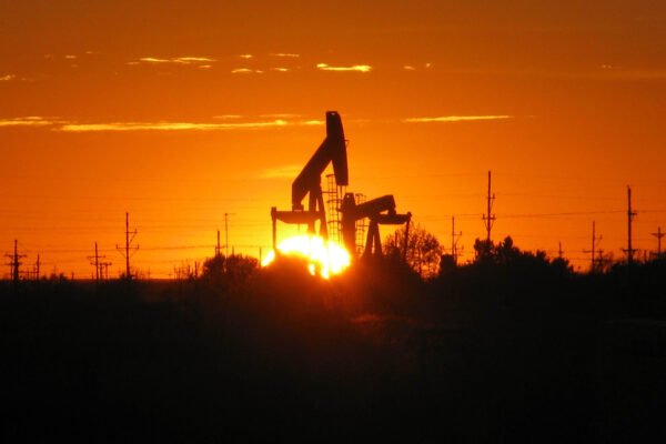 A pump jack silhouetted against the setting sun at an oil well in Texas.