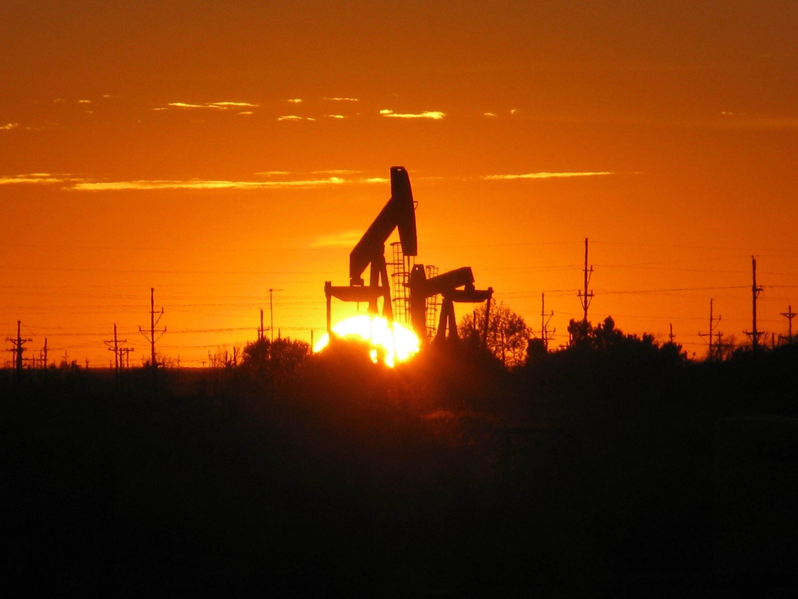 A pump jack silhouetted against the setting sun at an oil well in Texas.